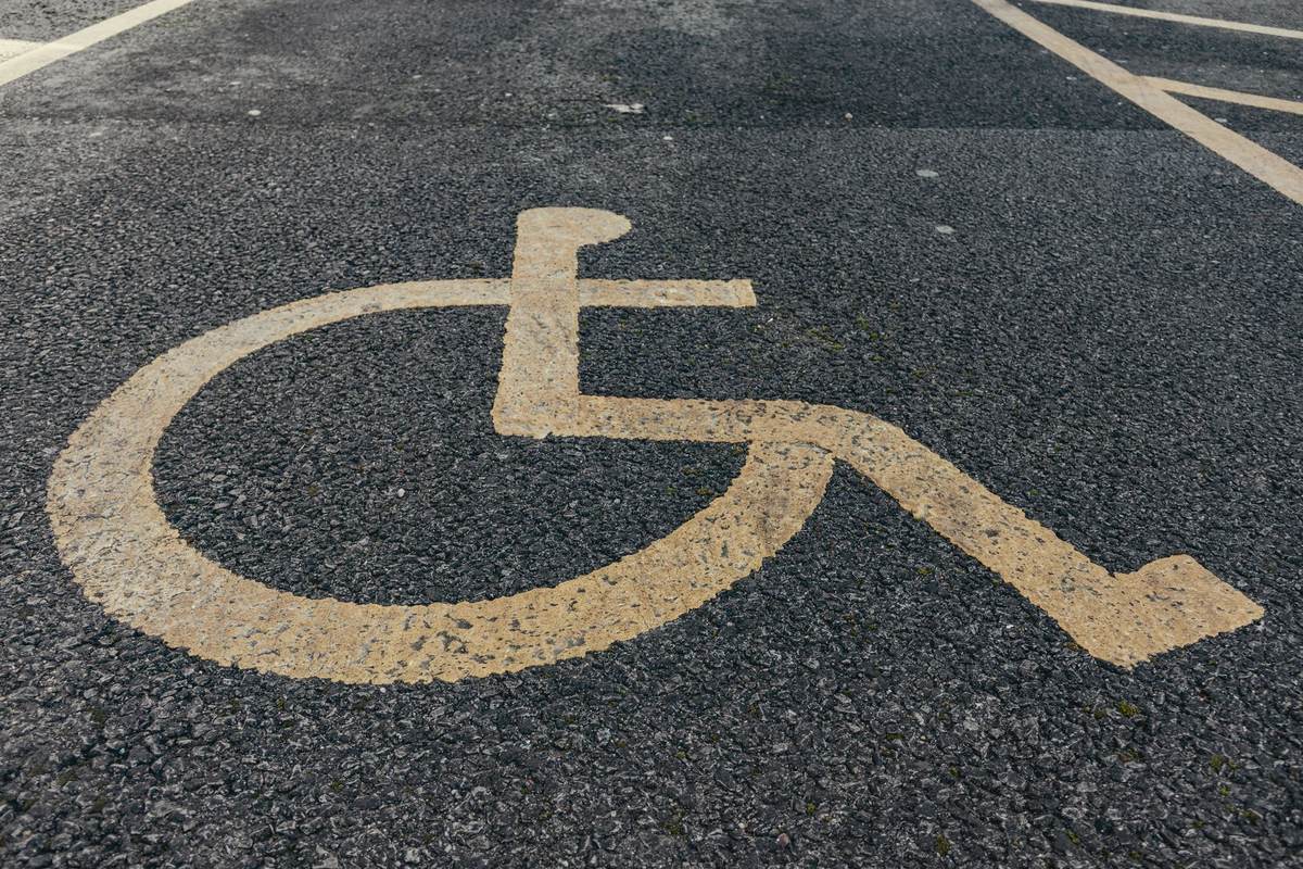 Blue wheelchair accessibility symbol painted on grey pavement