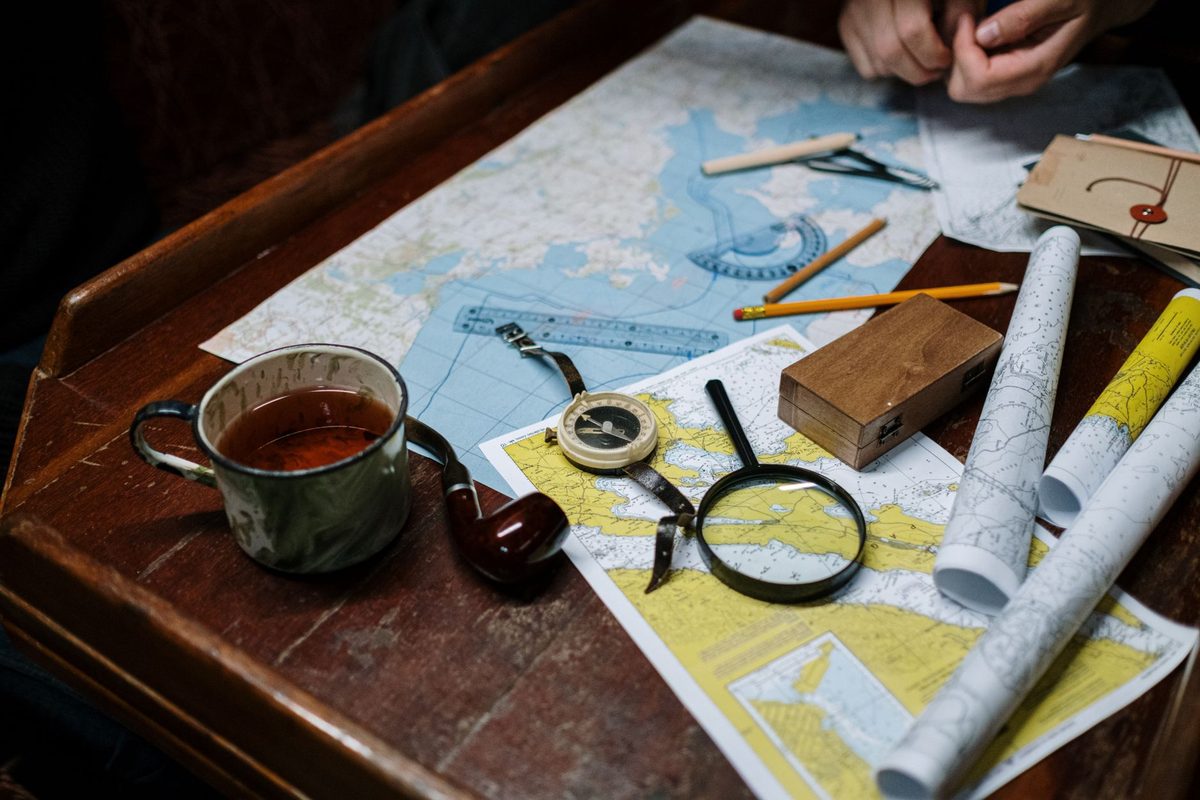 Paper maps and navigation tools laid out on a wooden table